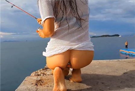 Brunette without panties by the sea catches fish <!-- width=
