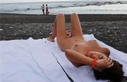 Naked brunette on public beach